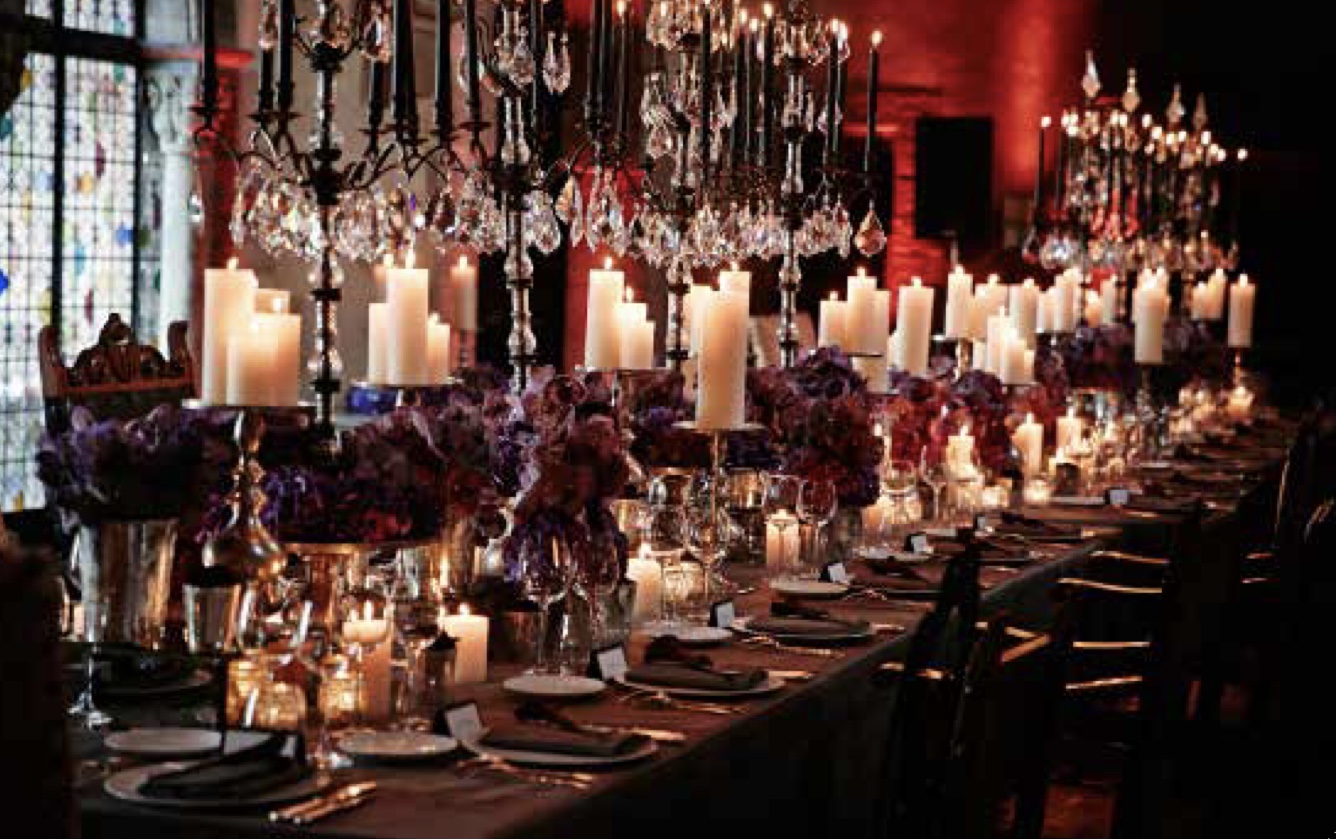 Private dinner in Cannes — long candlelit banquet table set with wrought-iron candelabras, crystal drops, and deep purple hydrangea arrangements