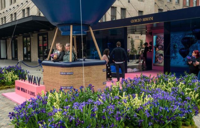 Detail of the Giorgio Armani My Way installation — guests inside the balloon basket surrounded by purple iris plantings