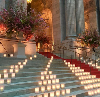 NY Fashion Week at the New York Public Library — marble steps lined with glowing votive candles and towering urns of pink bougainvillea at the entrance